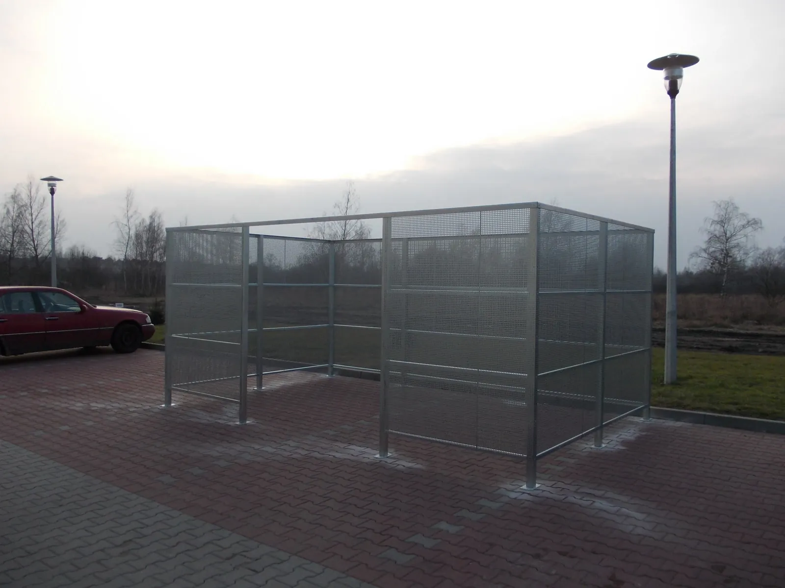 Stalowa klatka siatkowa na odpady przy budynku komercyjnym