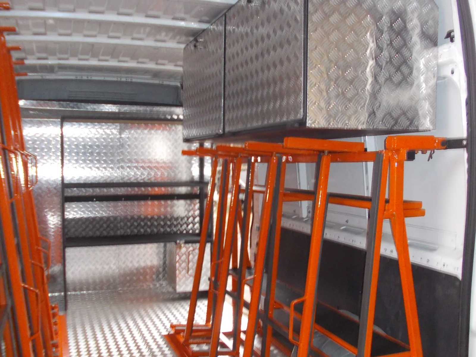 Zabudowa busa — pomarańczowe stojaki transportowe i aluminiowe szafki